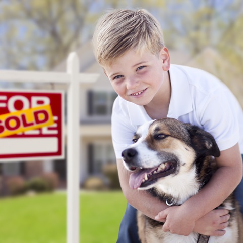 Boy with dog standing in front of a sold house