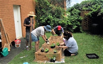 Group of people gardening outside apartment complex