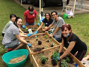 Group of people gardening outside apartment complex