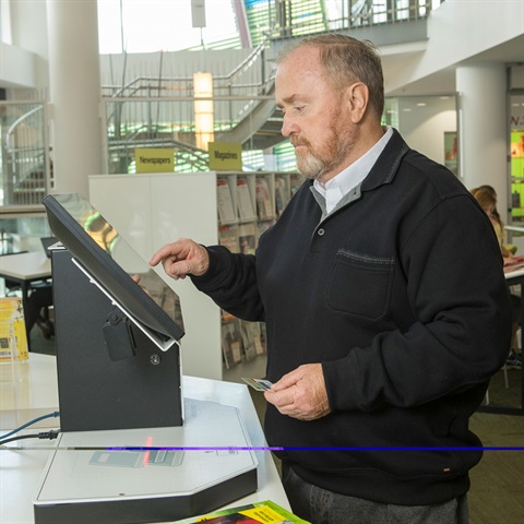 Man at library checking books out