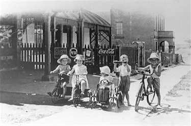 Coxs Road, North Ryde.  Bikes & trikes! Five children outside Hortons shop in Cox’s Road, North Ryde. The substantial two-storey building in the background is the North Ryde School of Arts, now the location of the North Ryde Community Hall and North Ryde Library. The children are identified as Barrie Hicks, Marie Hicks, Carol Keegan, Terry Morony and Fred Horton. Ryde Library Service. Acc. 5482143. North Ryde / 3