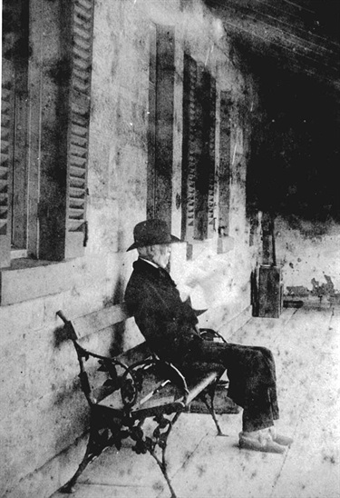 Charles Blaxland 1810-1888 on the verandah of Cleves, around 1888.  Charles Blaxland was the son of Gregory and Elizabeth Blaxland. Here we see him sitting on the verandah of his river-side house Cleves which was located on the western side of Charles Street, Putney. He must have had cold feet. Note his furry slippers! Ryde Library Service. Acc. 5482615. Blaxland family / 1