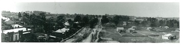 Panorama looking north-east along Lane Cove Road from the roof of Hampton Court, Ryde. The Hampton Court Tourist Residential was a multi-storey building located at the corner of what is now Devlin Street and Pope Street. Looking north, this photograph shows Lane Cove Road as a narrow unsealed road heading towards North Ryde which was dominated by orchards, market gardens and poultry farms. How different it looks today. Ryde Library Service. Acc. 5756154. Ryde / 25.