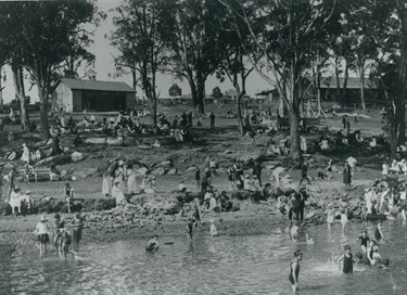 Swimmers and spectators at Meadowbank Baths c.1925. These baths and the adjoining recreation reserve were originally created through the efforts of a local progress association. Although bathers were protected from sharks by an enclosure, the baths were tidal and frequently muddy. They continued until c.1943 when effluent pollution from factories in Homebush Bay forced them to close. Ryde Library Service. Acc. 8502293. Meadowbank Baths / 2.