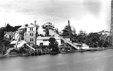 Rockend Cottage and Harold Meggitts linseed oil mill, Gladesville around 1924. In late 1923 Harold Meggitt established a linseed oil extraction plant on five acres of land at Punt Road, Gladesville. The site included Rockend Cottage, the former home of Emily Mary Barton. Linseed oil was used in the manufacture of paint and varnish, the formulation of putties and caulking compounds, in printing inks and linoleums. In later years a large silo erected as part of the plant was emblazoned with the company logo – a large cartoon figure of pipe-smoking Harold Meggitt in full stride. Ryde Library Service. Acc. 5075408. Halmeg Pty Ltd Gladesville / 1.