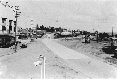 Looking south at Top Ryde c.1937. This is a fascinating photo showing Top Ryde, not long after Devlin Street had been constructed to make a more direct route for traffic that wanted to connect with the recently opened Ryde Bridge. On the left is the Rialto Theatre; the tram terminus is on the right. The construction of Devlin Street had the consequence of isolating the buildings in the centre of this photo and created what was for decades referred to as The Island Block. That later became the site for the Ryde Civic Centre and Centenary Hall. Ryde Library Service.