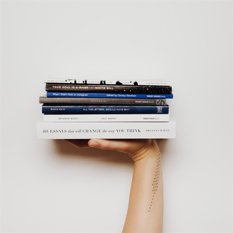 Photo of a hand holding up a pile of books