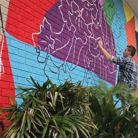 Artist Nick Fintan working on the Sager Place Mural