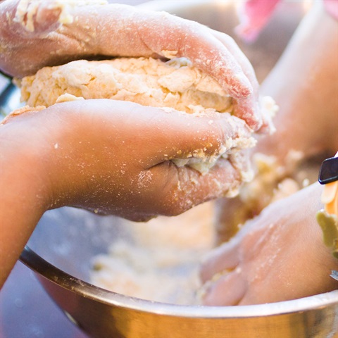 Children's hands in dough bowl