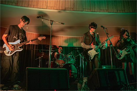 A band of four musicians play on stage