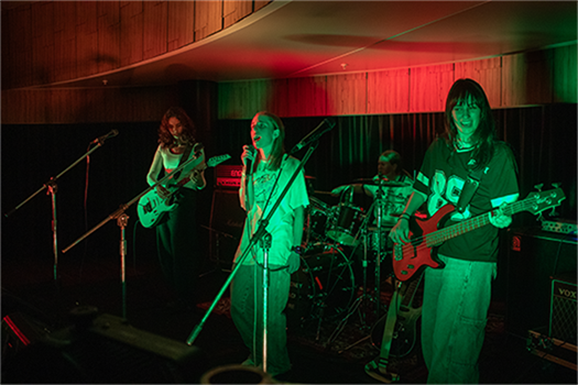 A band of four musicians play music on stage
