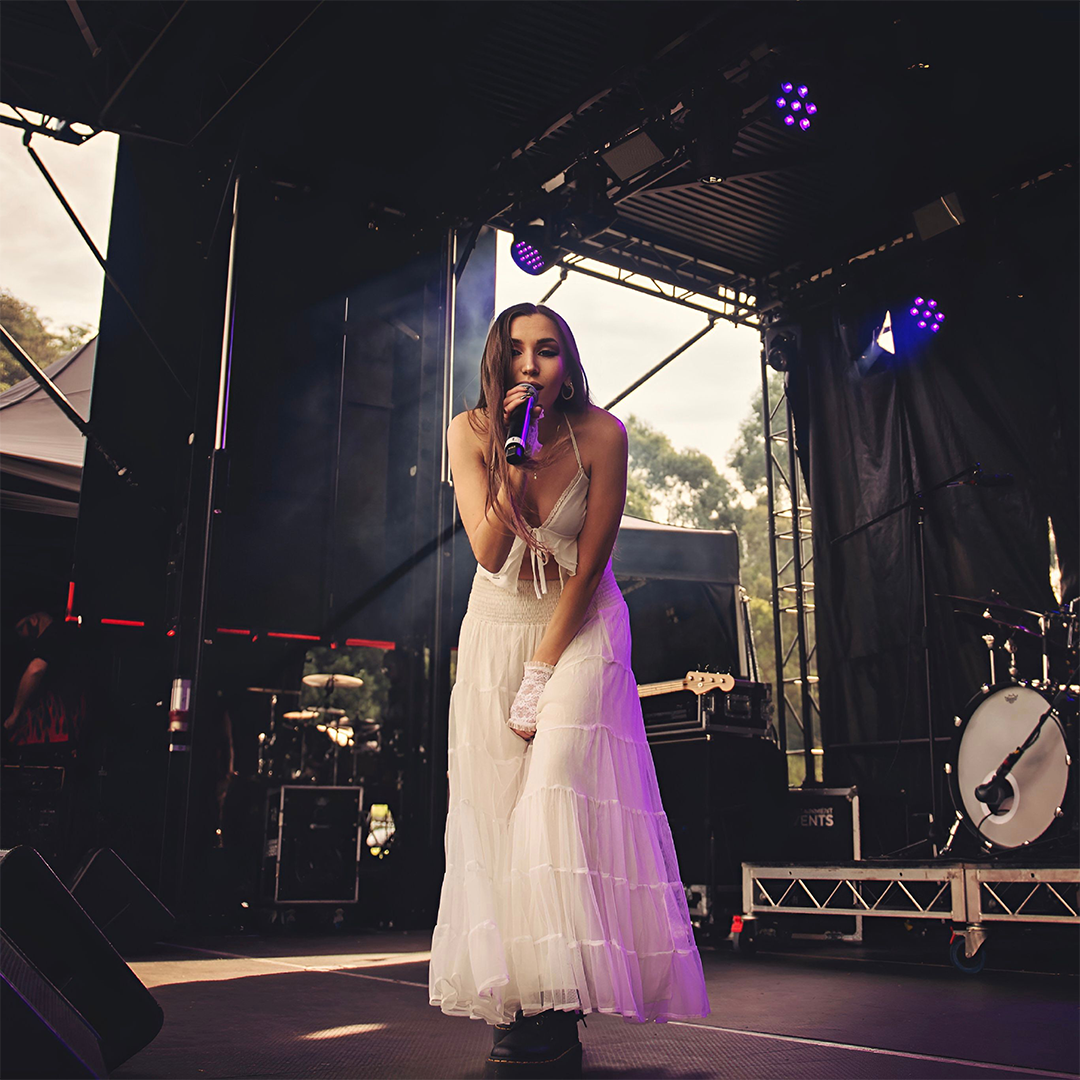 Female singer with microphone poses on stage toward the camera