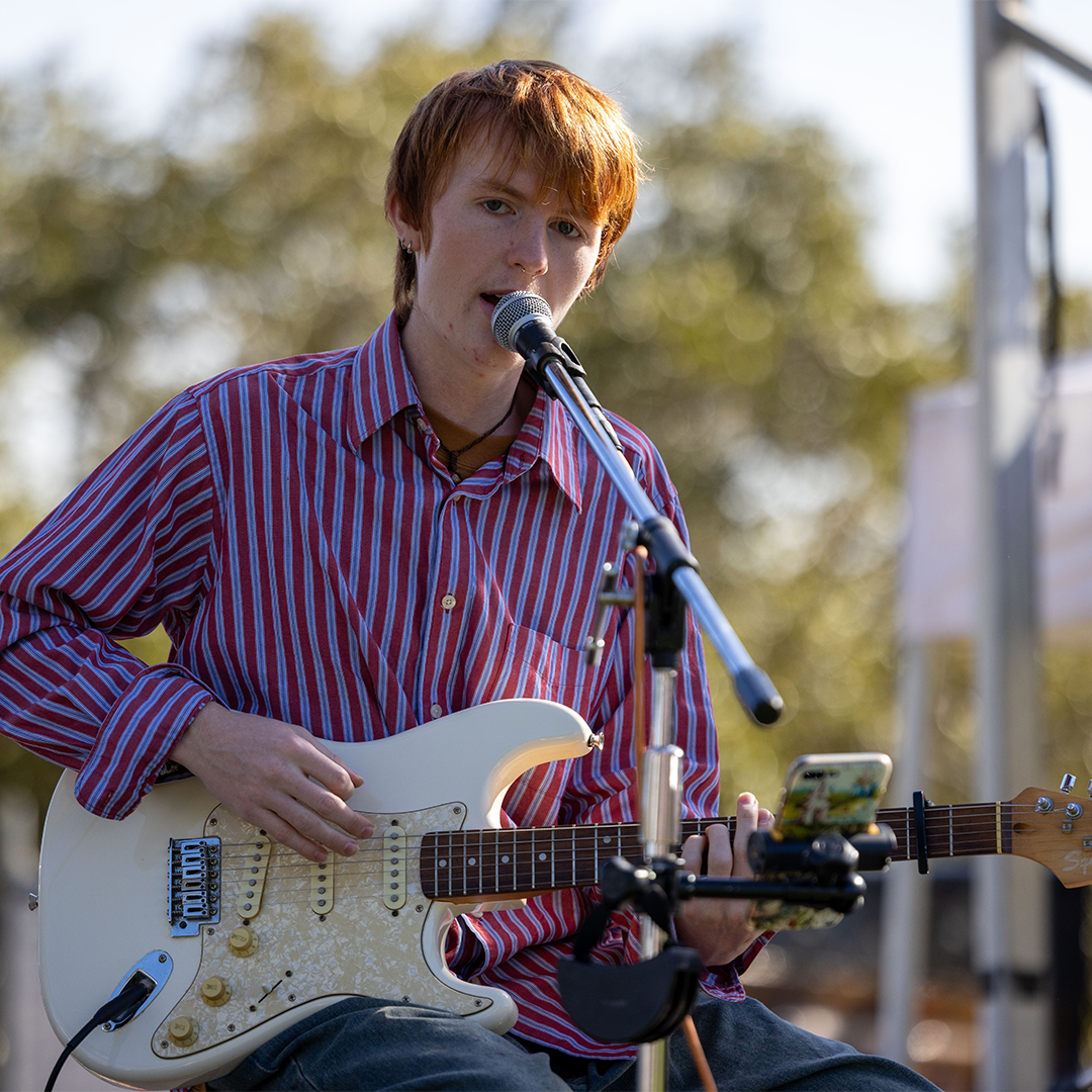 Young male plays a guitar and sings on stage