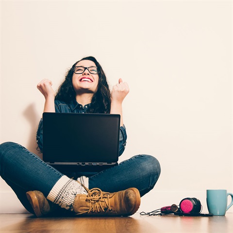 Woman on laptop smiling gleefully