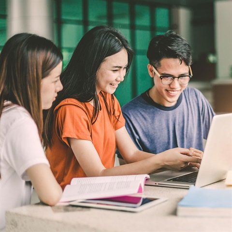 Young people smiling and looking at laptop