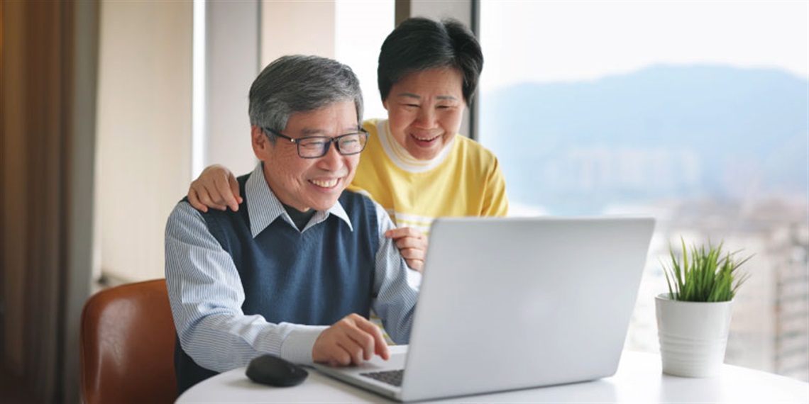 Seniors-using-laptop-near-window-at-home