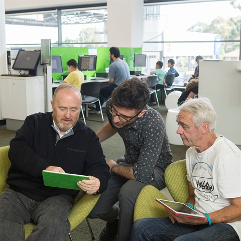 Two senior men getting assistance with tablets