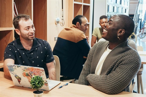 Two people having a fun discussion in front of a laptop inside a library