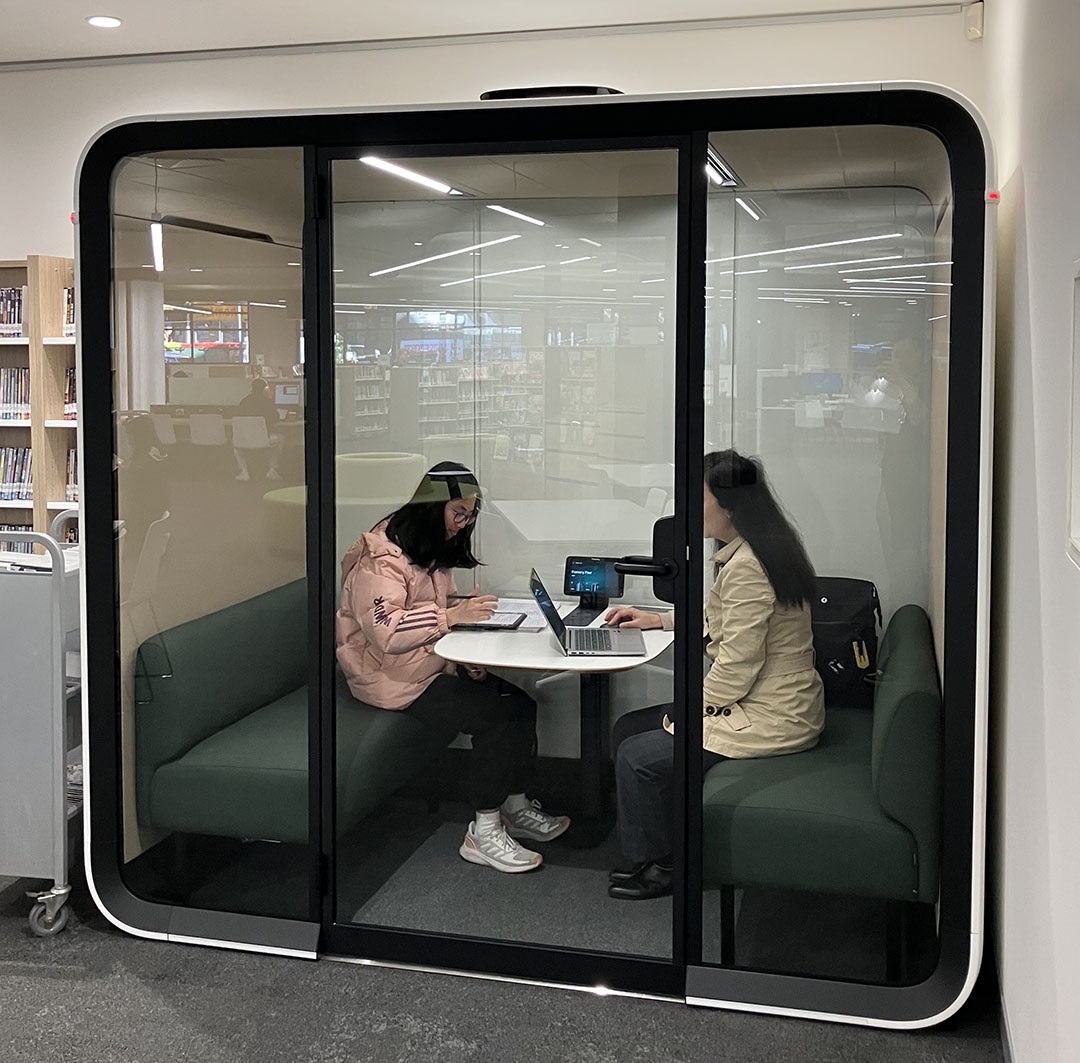Two people working inside a Quiet Pod inside the library