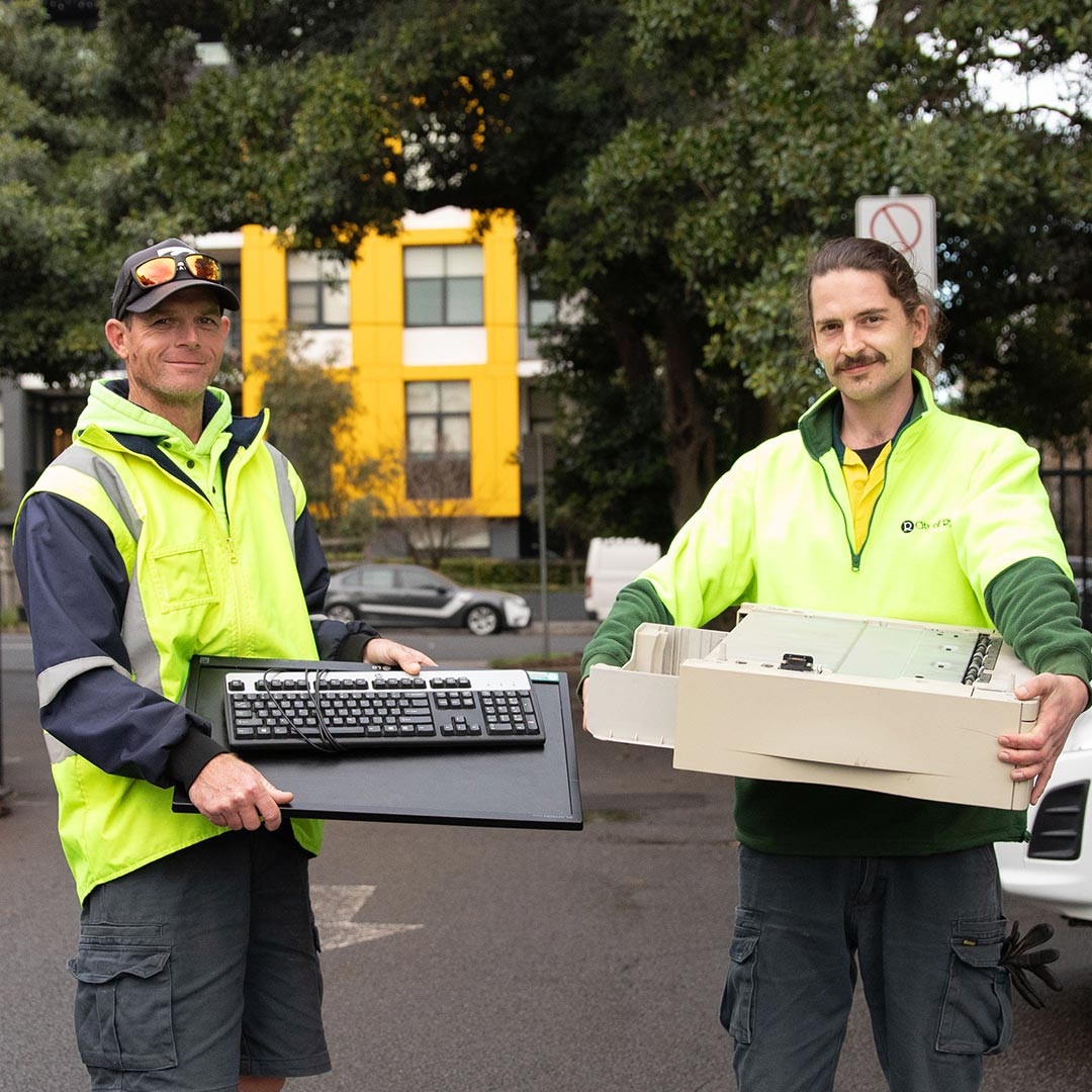 Photo of two men holding unwanted electronics