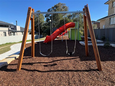 Swings with red tube slide visible in the background