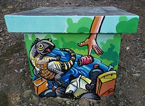 Painting of a lizard surrounded by rubbish on a storm water pit at Laurel Park Reserve 