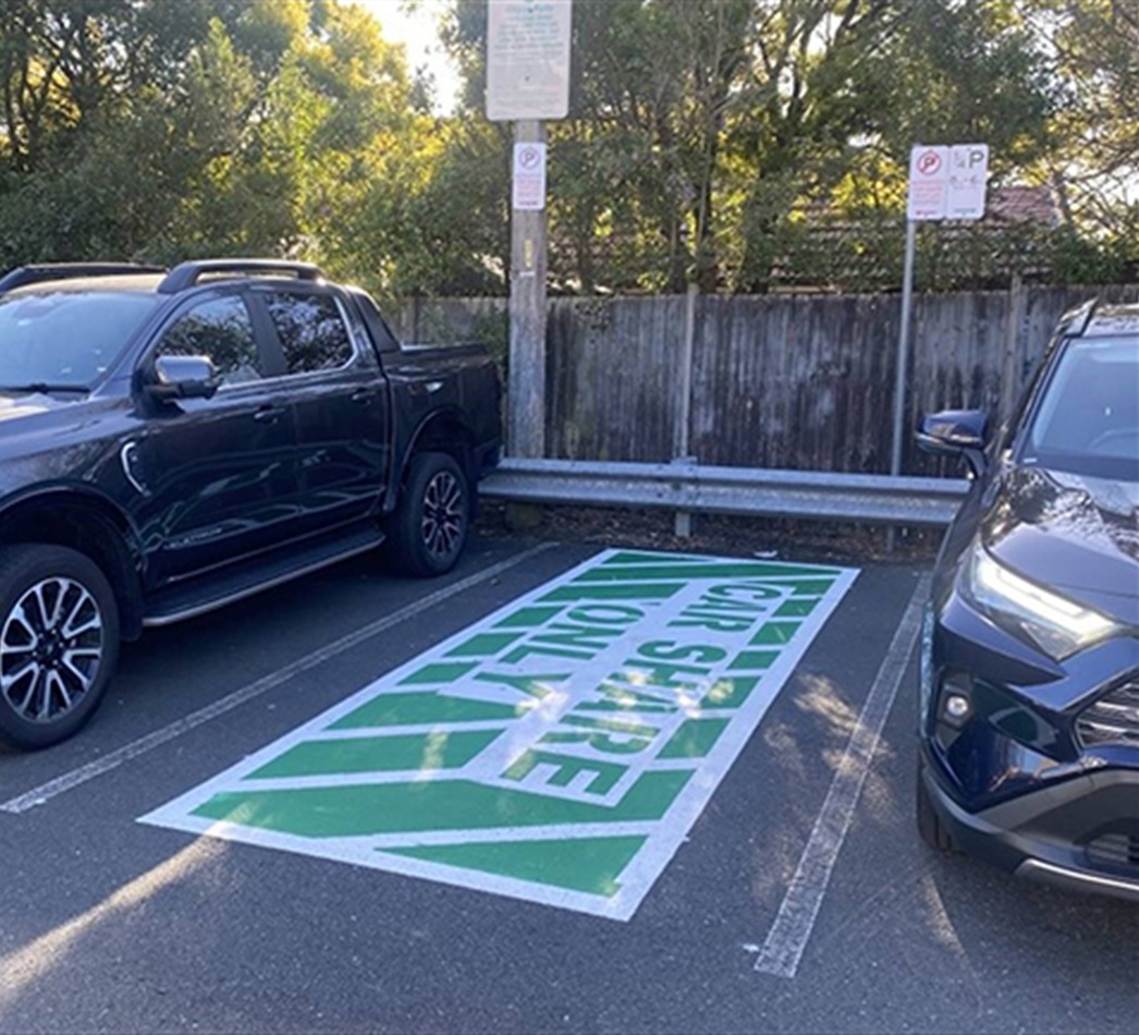 Empty car parking spot with text on the ground that says care share only