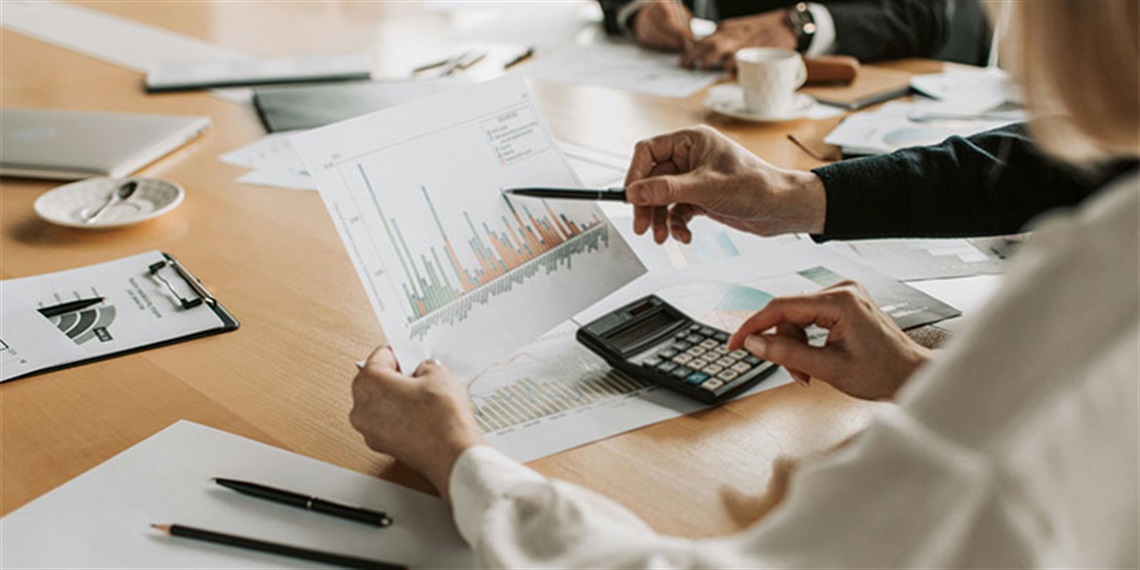 Image of people looking at financial charts around a boardroom table