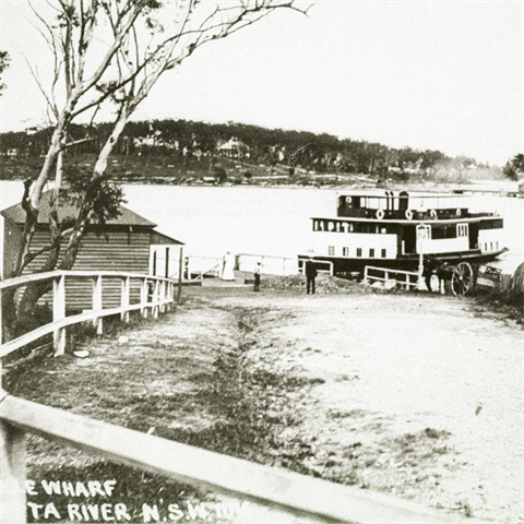 A dirt trail leading toward the water, a large boat sits docked.