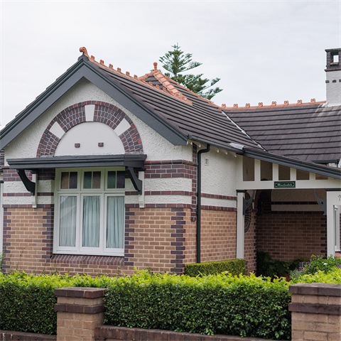 Single storey house with potted plants and low hedge plant outside