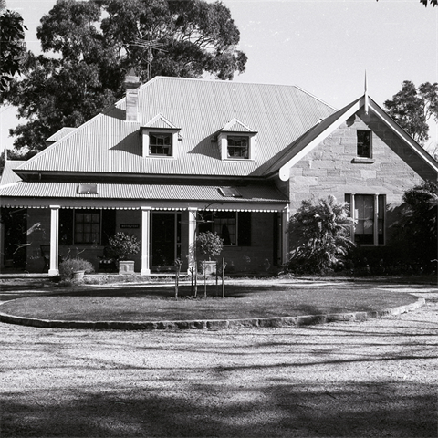 Single storey house with a water fountain out front surrounded by a neatly trimmed hedge