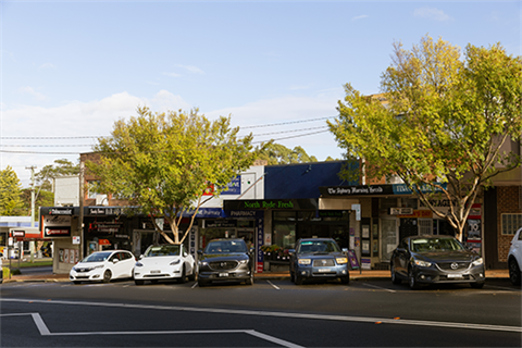 View of Blenheim Road shop fronts, two trees, and cars parked by the road