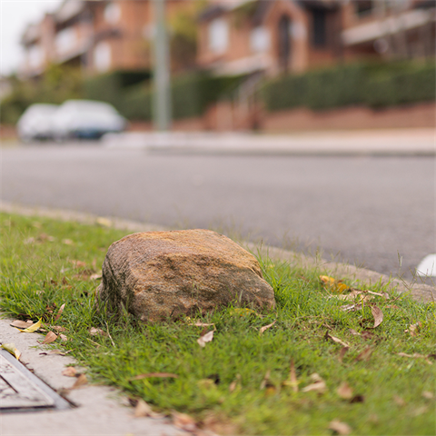 A square stone marker sits deep into a nature strip lawn