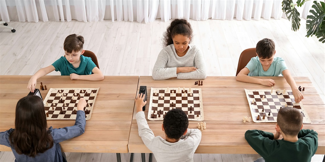 Children at a table playing games of chess